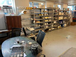 Reoler med indhold, samt møbler i rummet.