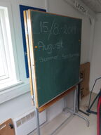 Ældre skoletavle på stativ. Kan foldes ud og der er tavler på begge sider.
