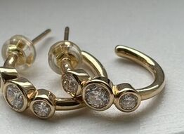 Et par ørestikker/hops af 14 kt. guld hver prydet med tre brillantslebne laboratorieskabte diamanter