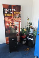 Indhold i hjørne af reoler, stativer samt planter i rummet