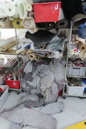 Indhold i reol af diverse tæpper, maling, diverse ruller mv.