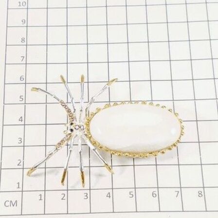 Unika broche, i form af en edderkop af guld og hvidguldbelagt sterlingsølv prydet med stor ca. 48 ct. oval cabochon