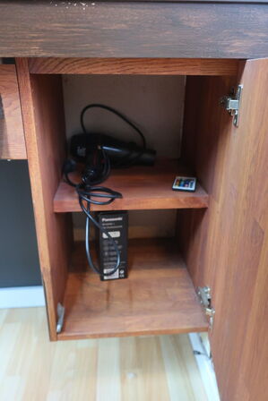 Vægmonteret møbel med spejl med bl.a. ventilator, varelager, hårtørrer, voks m.m. (indhold i reol i midten, medfølger ikke)