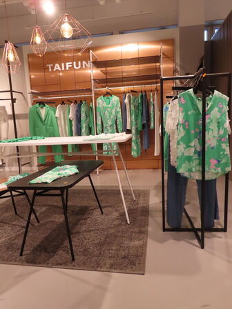 Udstilling med møbler, reol og tøjet på stativer og borde