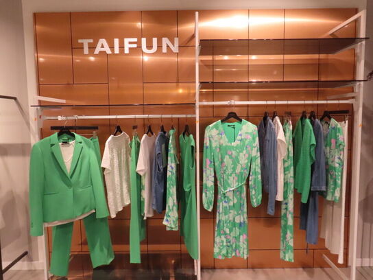 Udstilling med møbler, reol og tøjet på stativer og borde