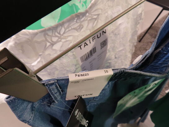 Udstilling med møbler, reol og tøjet på stativer og borde