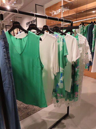 Udstilling med møbler, reol og tøjet på stativer og borde