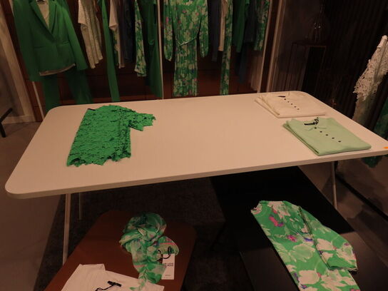 Udstilling med møbler, reol og tøjet på stativer og borde