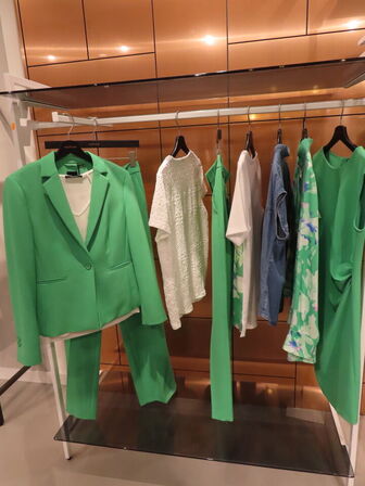 Udstilling med møbler, reol og tøjet på stativer og borde