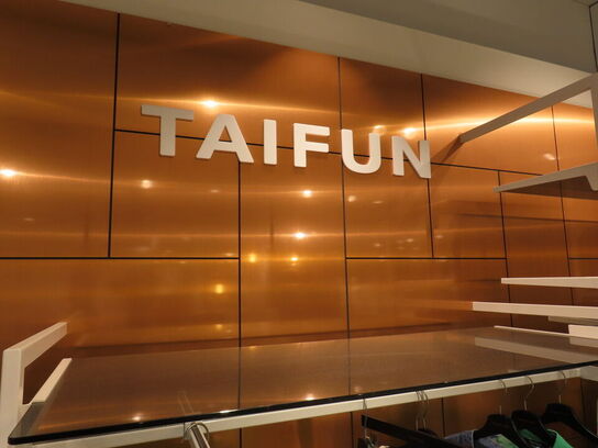 Udstilling med møbler, reol og tøjet på stativer og borde