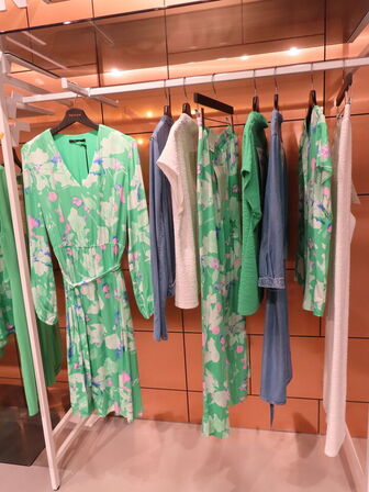 Udstilling med møbler, reol og tøjet på stativer og borde