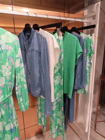 Udstilling med møbler, reol og tøjet på stativer og borde