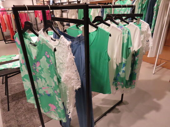 Udstilling med møbler, reol og tøjet på stativer og borde