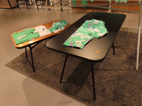 Udstilling med møbler, reol og tøjet på stativer og borde