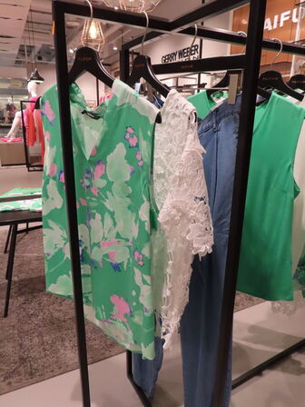 Udstilling med møbler, reol og tøjet på stativer og borde