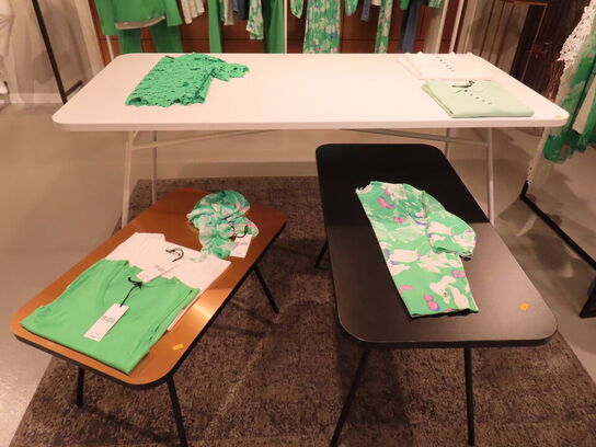 Udstilling med møbler, reol og tøjet på stativer og borde