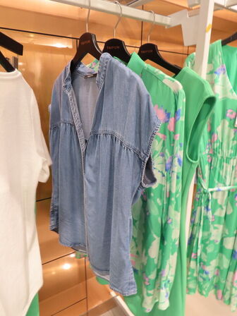 Udstilling med møbler, reol og tøjet på stativer og borde