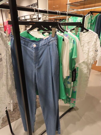 Udstilling med møbler, reol og tøjet på stativer og borde