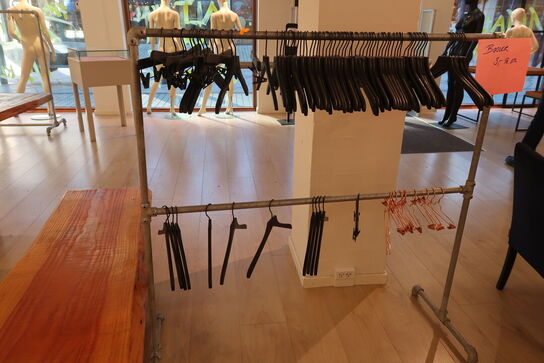 Tøjtstativ med bøjler samt stænger på væg