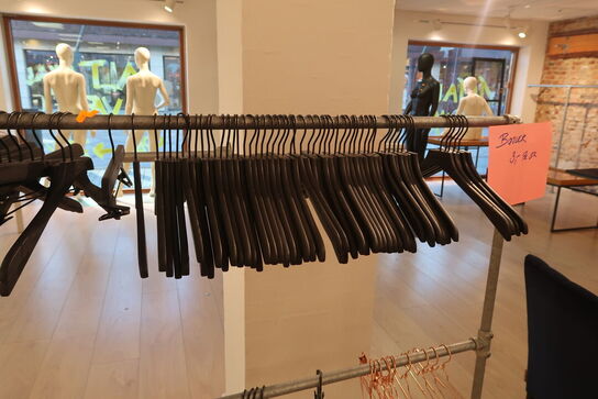 Tøjtstativ med bøjler samt stænger på væg