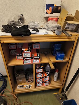 Indhold på reol (PASLODE stifter m.v.) samt hammer, målepind m.m.