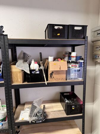 Indhold på reol af diverse spraydåser, fuge mv.