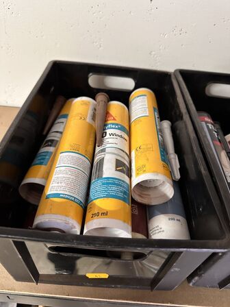 Indhold på reol af diverse spraydåser, fuge mv.