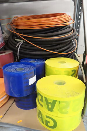 Indhold på reol af diverse ledninger, markeringsbånd mv.