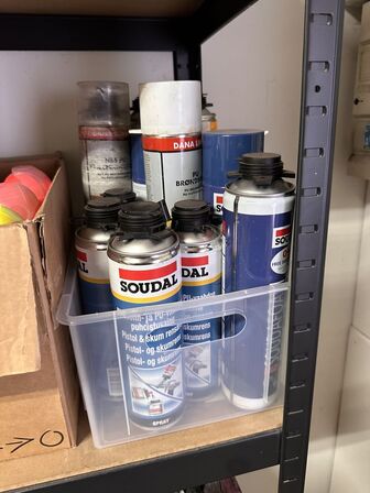 Indhold på reol af diverse spraydåser, fuge mv.
