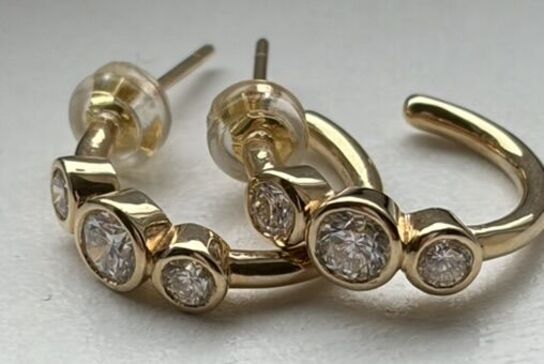 Et par ørestikker/hops af 14 kt. guld hver prydet med tre brillantslebne laboratorieskabte diamanter