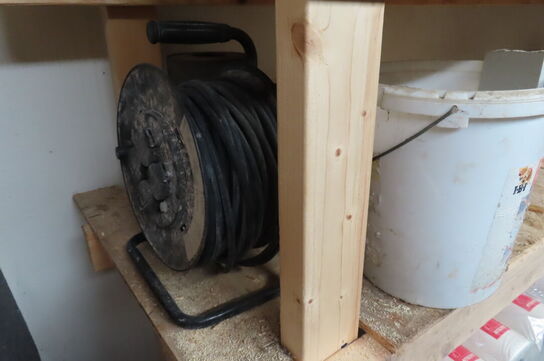 Indhold på reol af diverse papir, murerbaljer, kabeltrommel mv.