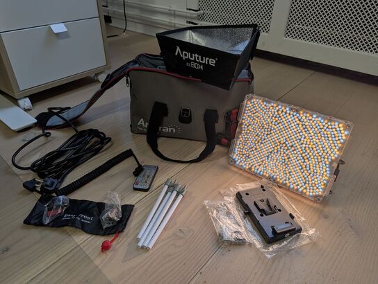 Amaran LED Tri-8C light kit, including panel, batteries, mounting gear, and carrying bag. -APUTURE