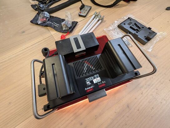 Amaran LED Tri-8C light kit, including panel, batteries, mounting gear, and carrying bag. -APUTURE