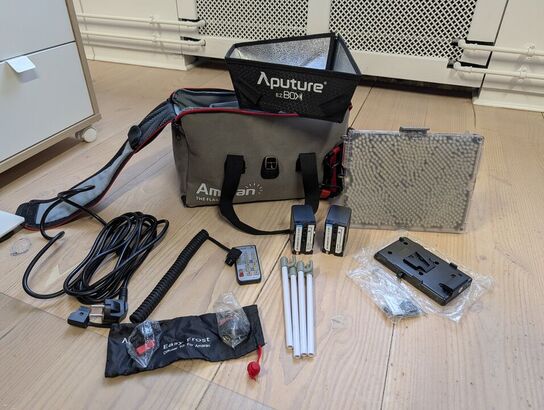 Amaran LED Tri-8C light kit, including panel, batteries, mounting gear, and carrying bag. -APUTURE