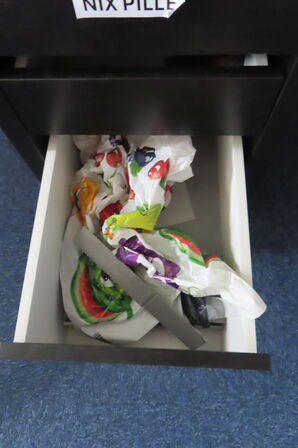 Indhold i hjørne af reoler, stativer samt planter i rummet