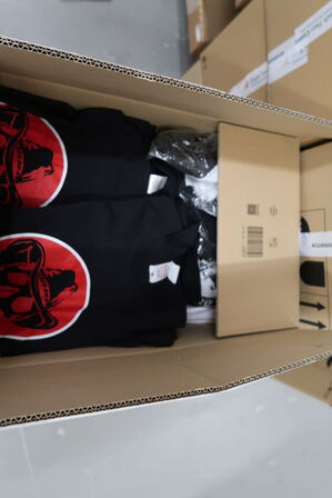 Div. Papkasser med merchandise bl.a. tøj m.m.